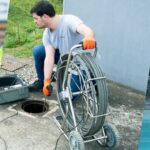 Technicien utilisant une caméra d'inspection avec sonde de détection sur un réseau enterré, dévidoir et récepteur en main